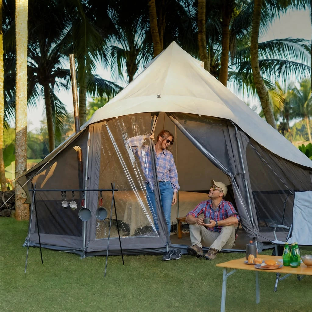 Two campers relaxing at the entrance of a LIGHT bell tent in a palm-tree campsite